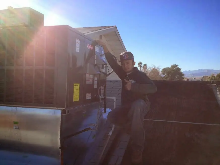 HVAC technician performing Boiler Repair on a rooftop unit in Victor